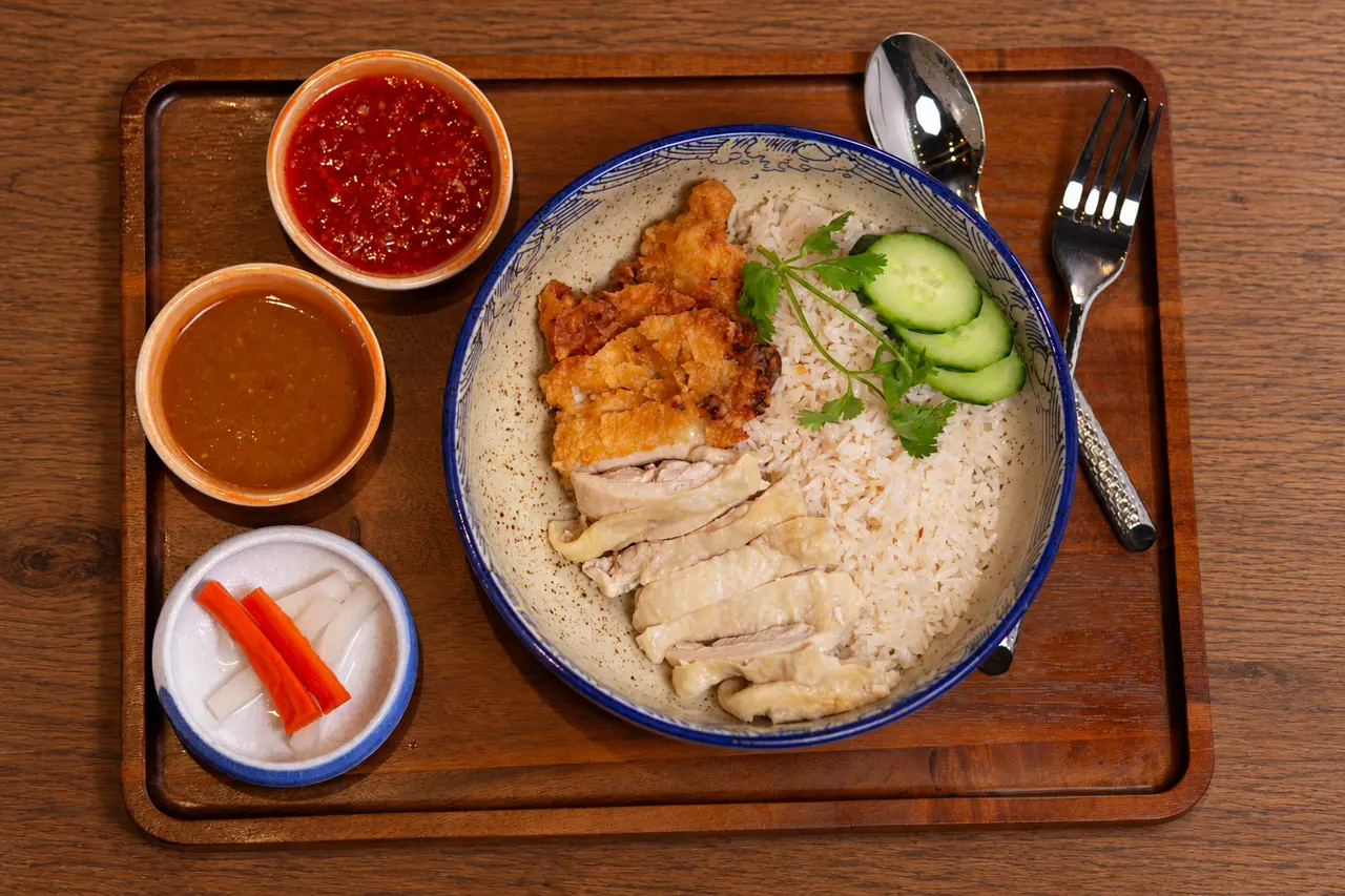 Kao Man Kai Duo with braised and crispy chicken, rice, cucumber, and sauces.