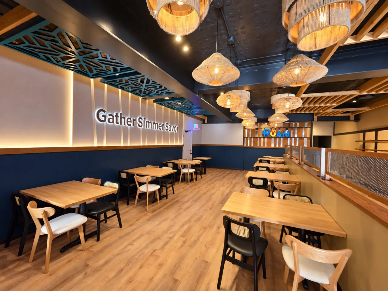 RUAM dining room with warm wood tables, woven pendant lights, and deep teal walls.
