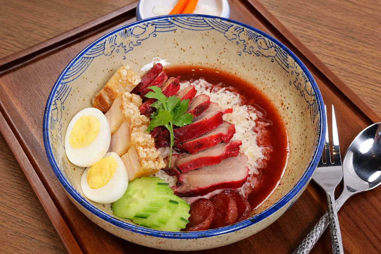 Moo Dang and Moo Krob rice bowl with barbecue pork, crispy pork belly, sausage, and egg.